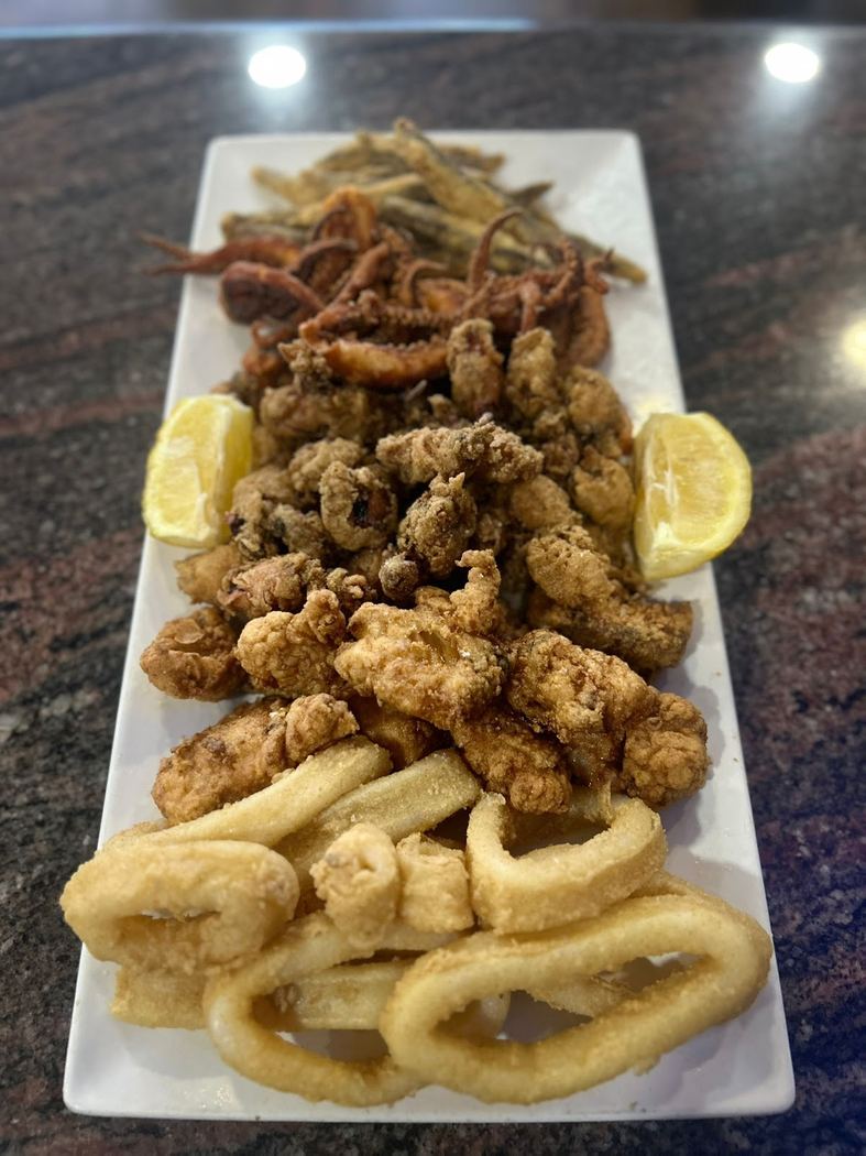 Fritura variada de pescado con calamares, boquerones y pulpitos, servida caliente.